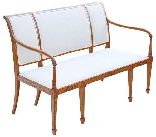 fig 2. A late 19th-century painted satinwood sofa featuring cream fabric upholstery, three backrest panels, curved armrests, and hand-painted floral detailing on the timber frame.