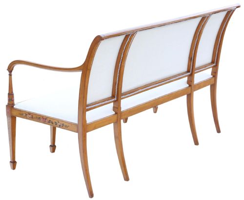 fig 3. A late 19th-century painted satinwood sofa featuring cream fabric upholstery, three backrest panels, curved armrests, and hand-painted floral detailing on the timber frame.
