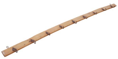 fig 1. A long horizontal pine timber rail fitted with nine spaced, hand-forged wrought iron hooks with pointed backplates.