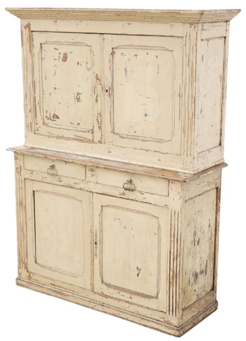 fig 2. A 19th-century two-tier wooden storage cupboard painted in distressed cream, featuring fluted side details, upper and lower double doors with fielded panels, and two central drawers.