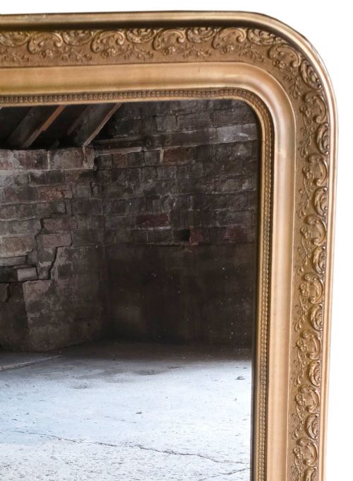 fig 2. A large late nineteenth-century rectangular overmantel mirror with rounded upper corners, an intricate foliate carved gilt frame, and a beaded inner border.