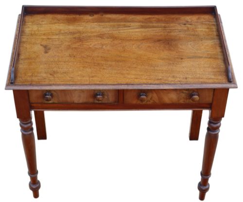 fig 1. A 19th-century mahogany writing table featuring a gallery top, two frieze drawers with wooden knob handles, and turned legs.