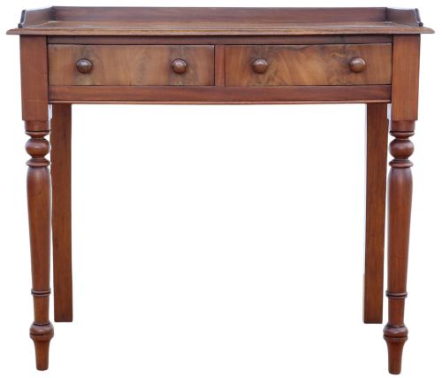 fig 2. A 19th-century mahogany writing table featuring a gallery top, two frieze drawers with wooden knob handles, and turned legs.