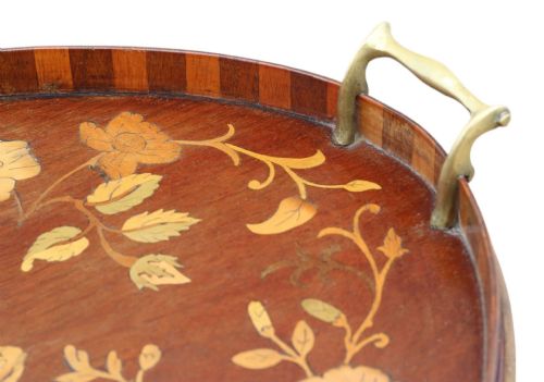 fig 1. An oval mahogany serving tray decorated with floral marquetry inlay and fitted with twin brass handles.