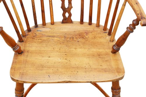fig 4. A nineteenth-century wooden Windsor armchair featuring a curved hoop back, a decorative central splat, shaped elm seat, and turned legs with a crinoline stretcher.