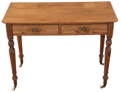 fig 1. A 19th-century pitch pine writing table with two drawers, brass handles, turned legs, and metal castors.
