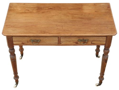 fig 2. A 19th-century pitch pine writing table with two drawers, brass handles, turned legs, and metal castors.