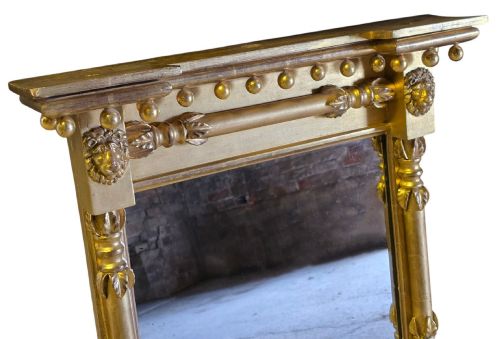 fig 1. A rectangular 19th-century Regency giltwood pier mirror featuring a breakfront cornice with sphere mouldings, lion mask corner blocks, and detailed column sides.
