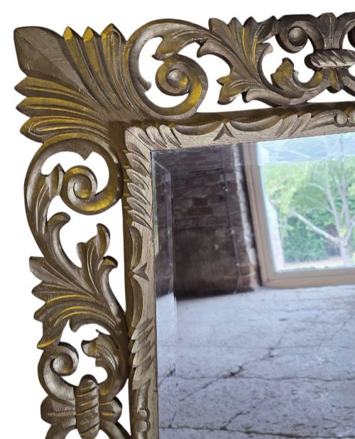 fig 2. A rectangular bevelled glass mirror set within an intricately carved gold giltwood frame with openwork acanthus leaves and scrollwork.