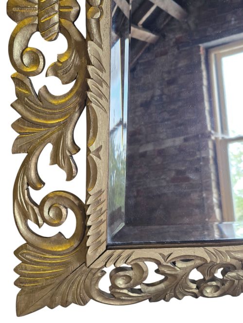 fig 5. A rectangular bevelled glass mirror set within an intricately carved gold giltwood frame with openwork acanthus leaves and scrollwork.