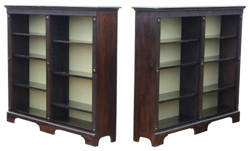 fig 1. A matching pair of dark oak double-bay bookcases featuring fluted vertical trim, adjustable shelving, green pattern-lined interiors, and bracket bases.