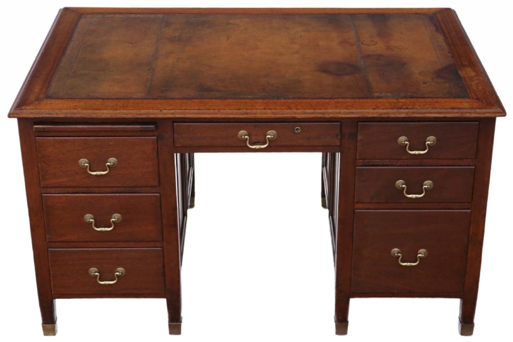 A mahogany twin pedestal writing desk featuring a worn brown leather top insert, multiple drawers with brass handles, and square tapered feet.