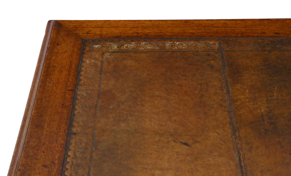 A mahogany twin pedestal writing desk featuring a worn brown leather top insert, multiple drawers with brass handles, and square tapered feet. View V