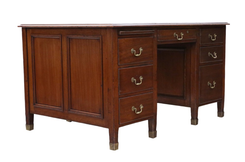 A mahogany twin pedestal writing desk featuring a worn brown leather top insert, multiple drawers with brass handles, and square tapered feet. View XI
