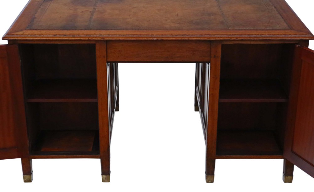 A mahogany twin pedestal writing desk featuring a worn brown leather top insert, multiple drawers with brass handles, and square tapered feet. View XIII