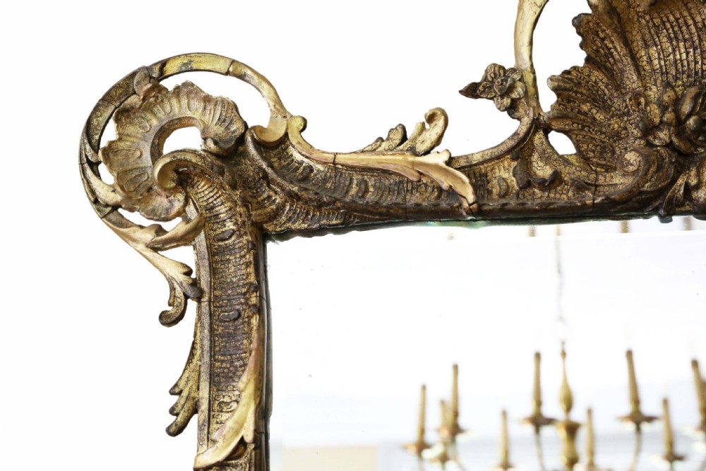 An ornate early 19th-century Rococo Revival style rectangular giltwood wall mirror featuring elaborate scrolling acanthus leaf carvings and a central shell cresting. View III