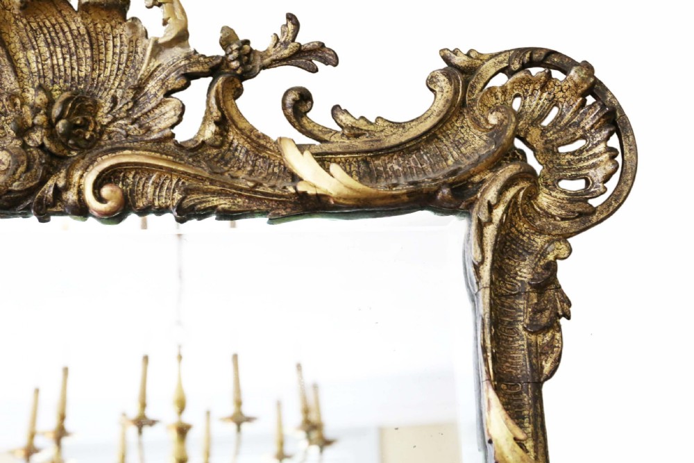 An ornate early 19th-century Rococo Revival style rectangular giltwood wall mirror featuring elaborate scrolling acanthus leaf carvings and a central shell cresting. View IV