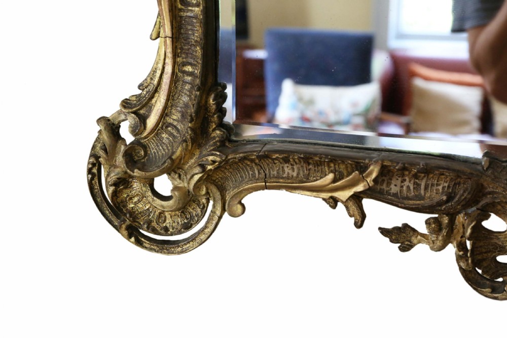 An ornate early 19th-century Rococo Revival style rectangular giltwood wall mirror featuring elaborate scrolling acanthus leaf carvings and a central shell cresting. View VII