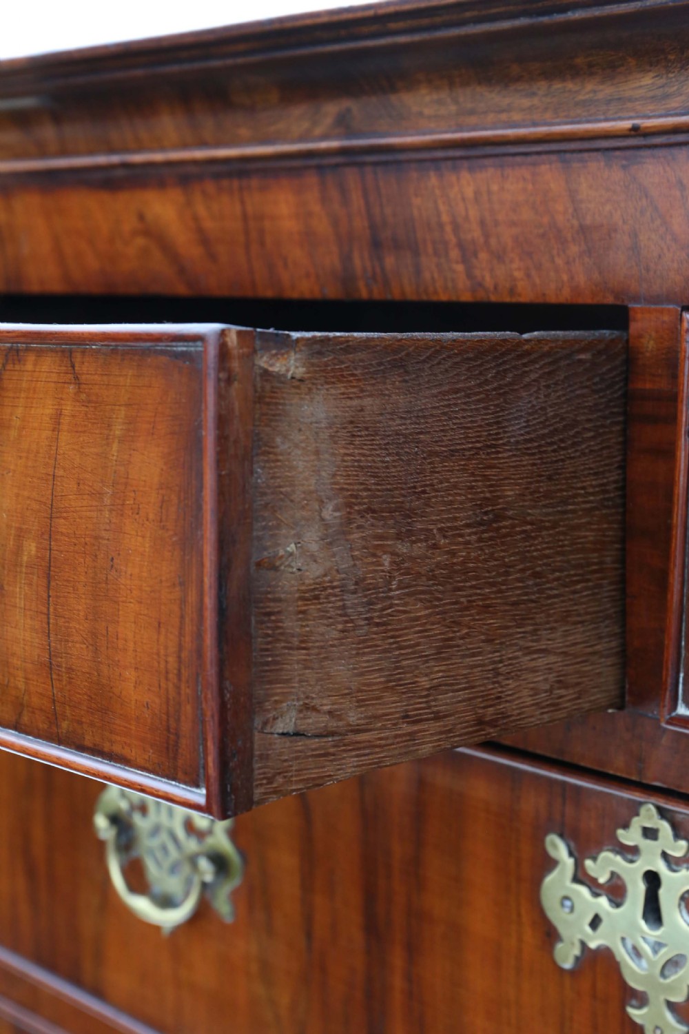 A Georgian figured walnut chest of drawers featuring ornate brass handles and escutcheons, set on cabriole legs with carved claw and ball feet. View VI