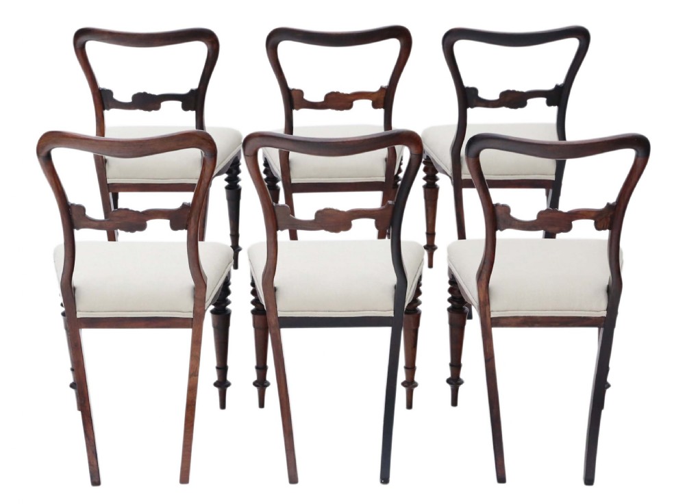 A set of six Victorian rosewood balloon back dining chairs featuring carved central splats, turned front legs, and cream upholstered seats. View II