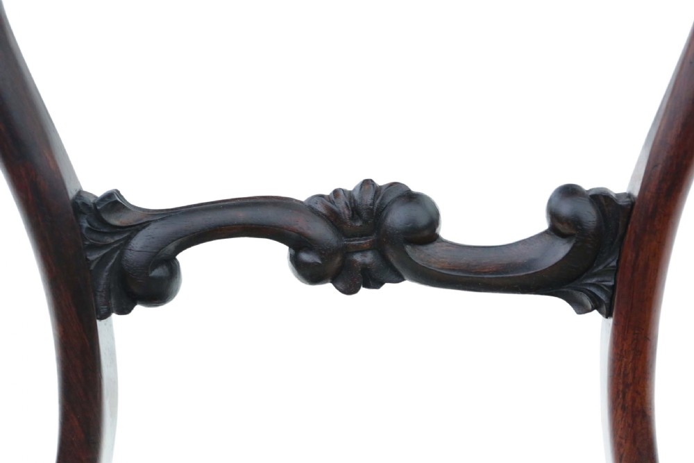 A set of six Victorian rosewood balloon back dining chairs featuring carved central splats, turned front legs, and cream upholstered seats. View VI