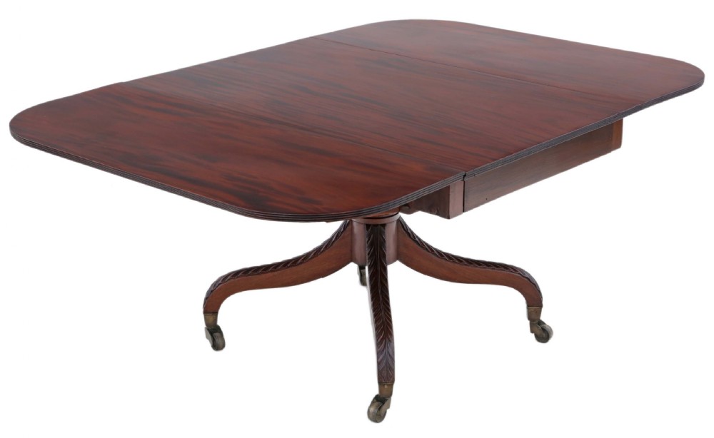 A Regency period Cuban mahogany drop leaf dining table extended with a central pedestal and four reeded splayed legs on brass castors.