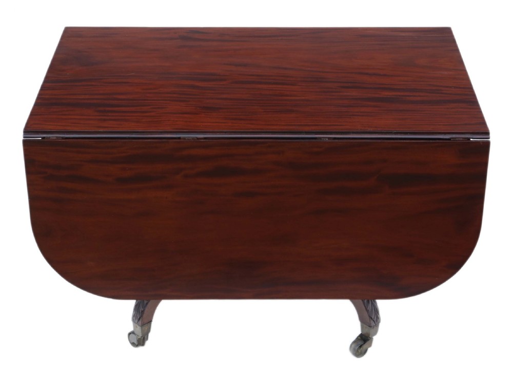 A Regency period Cuban mahogany drop leaf dining table extended with a central pedestal and four reeded splayed legs on brass castors. View III