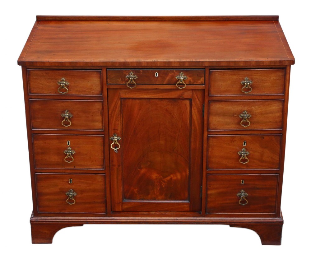 A late Georgian mahogany kneehole desk circa 1820 featuring a central recessed cupboard, eight side drawers with brass swing handles, and bracket feet.