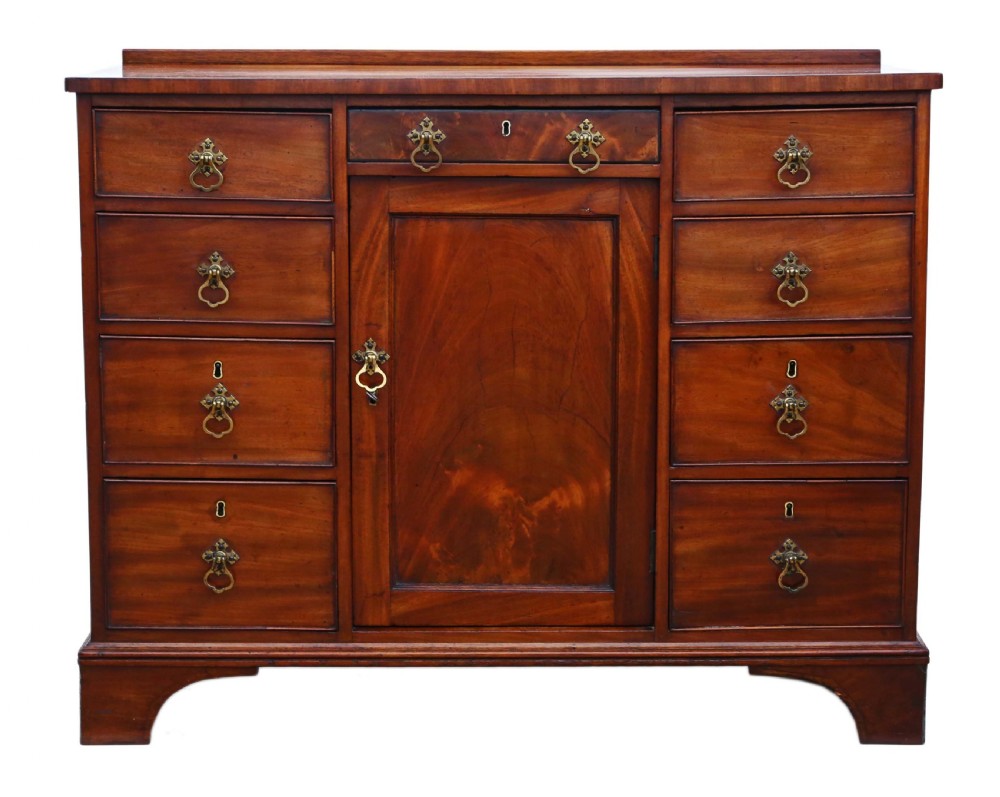 A late Georgian mahogany kneehole desk circa 1820 featuring a central recessed cupboard, eight side drawers with brass swing handles, and bracket feet. View II