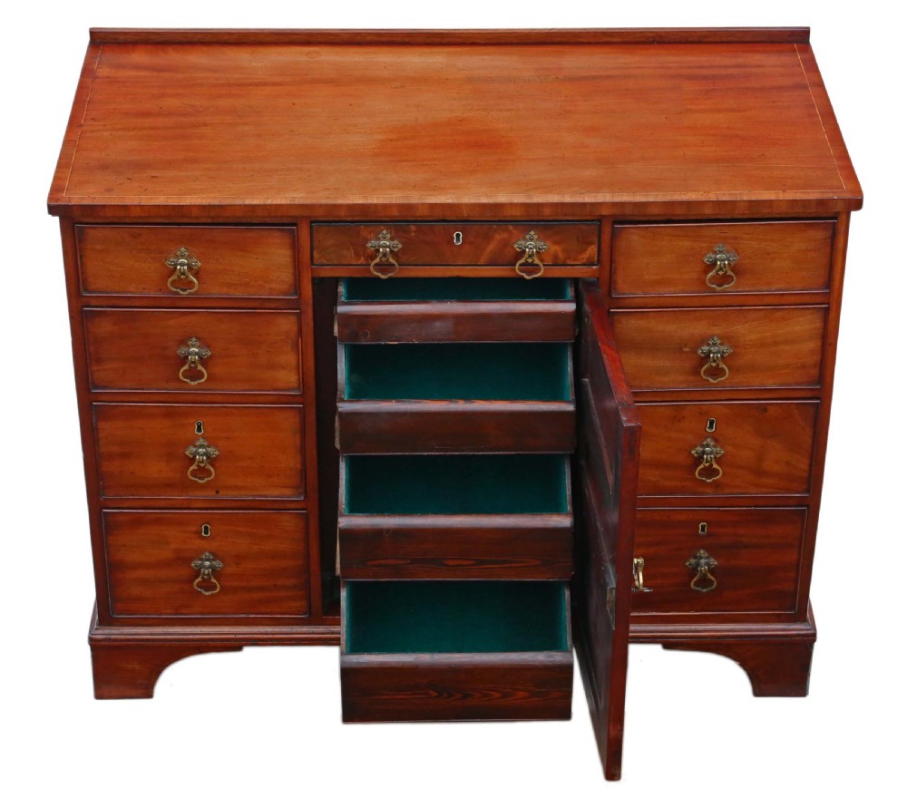 A late Georgian mahogany kneehole desk circa 1820 featuring a central recessed cupboard, eight side drawers with brass swing handles, and bracket feet. View V