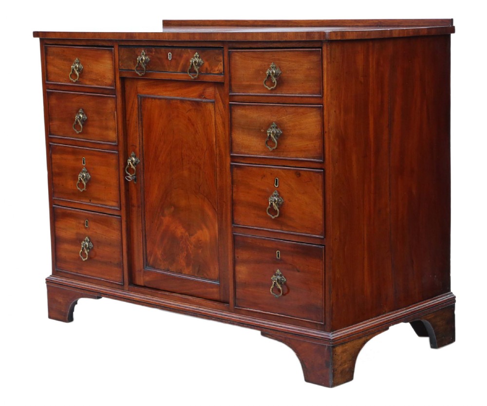A late Georgian mahogany kneehole desk circa 1820 featuring a central recessed cupboard, eight side drawers with brass swing handles, and bracket feet. View VI