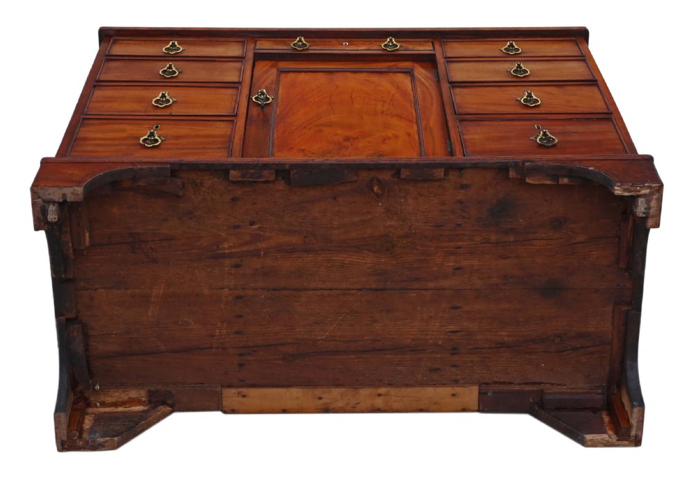 A late Georgian mahogany kneehole desk circa 1820 featuring a central recessed cupboard, eight side drawers with brass swing handles, and bracket feet. View X