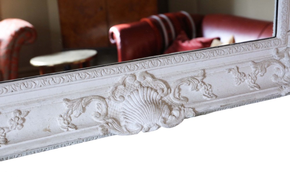 A large rectangular overmantel mirror featuring an off-white carved gesso frame decorated with scallop shell motifs, foliage, and corner crests. View VII