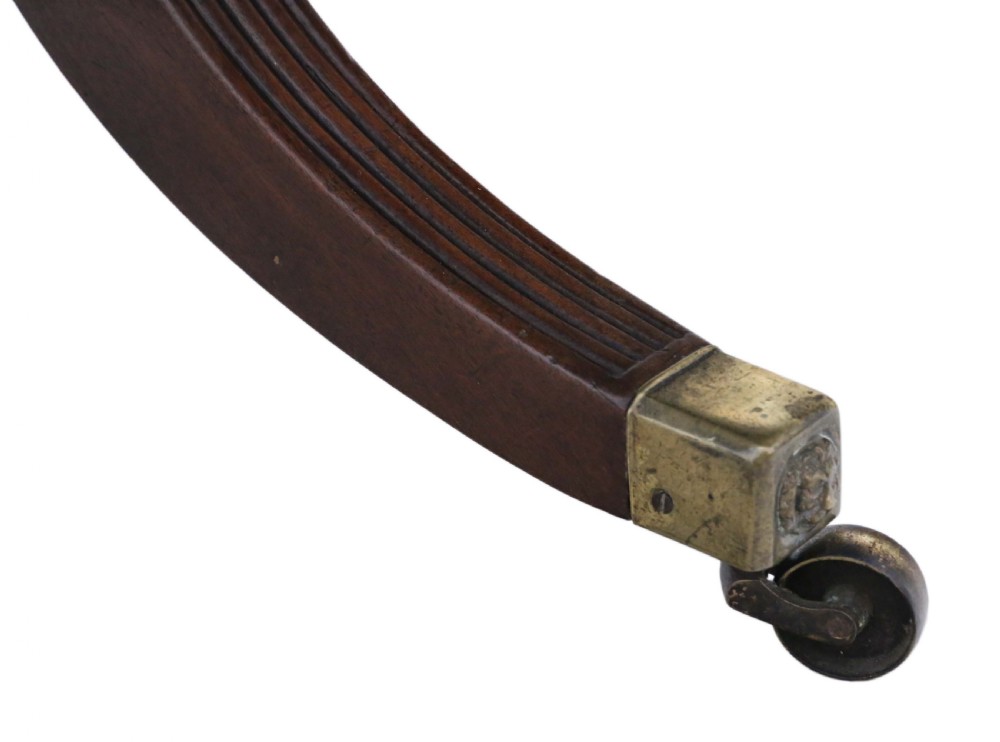 A Regency mahogany tilt-top loo table shown in a tilted position with a central pedestal and four reeded legs fitted with brass castors. View VI