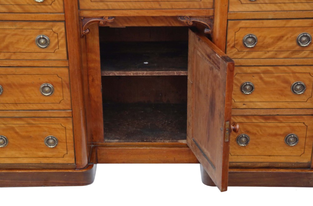 A Victorian satin walnut pedestal desk featuring a green gilt-tooled leather writing surface, multiple drawers with drop ring handles, and a central cupboard door. View IX