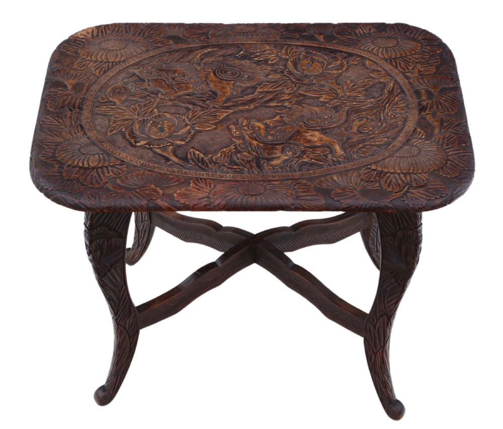 A dark carved hardwood table featuring detailed relief carvings of floral patterns on the top, curved cabriole legs, and an X-shaped stretcher. View II
