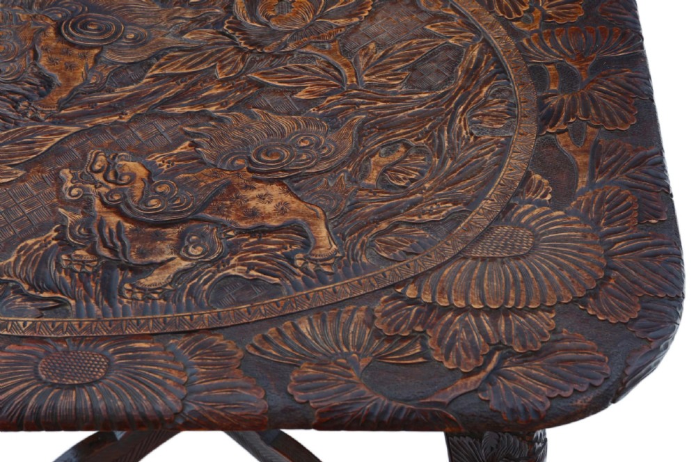 A dark carved hardwood table featuring detailed relief carvings of floral patterns on the top, curved cabriole legs, and an X-shaped stretcher. View III
