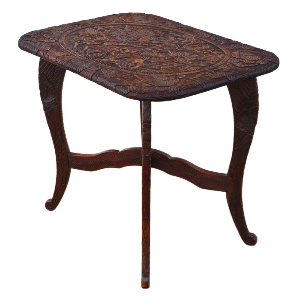 A dark carved hardwood table featuring detailed relief carvings of floral patterns on the top, curved cabriole legs, and an X-shaped stretcher. View IX