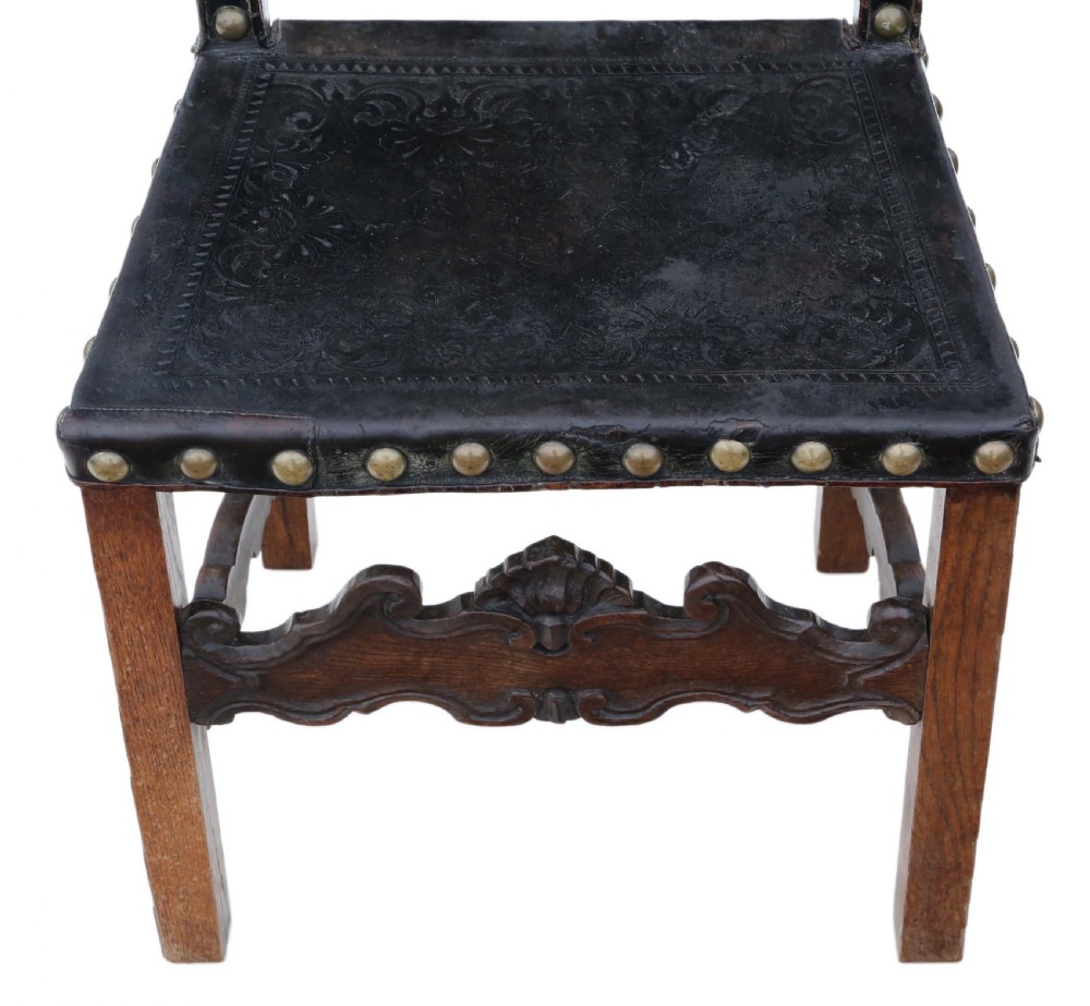 An antique Portuguese oak side chair featuring dark embossed leather upholstery with large brass studs and a carved lower stretcher. View VI