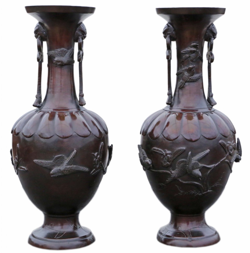 A pair of large Japanese dark bronze presentation vases featuring high-relief bird motifs alongside stylized drop handles.