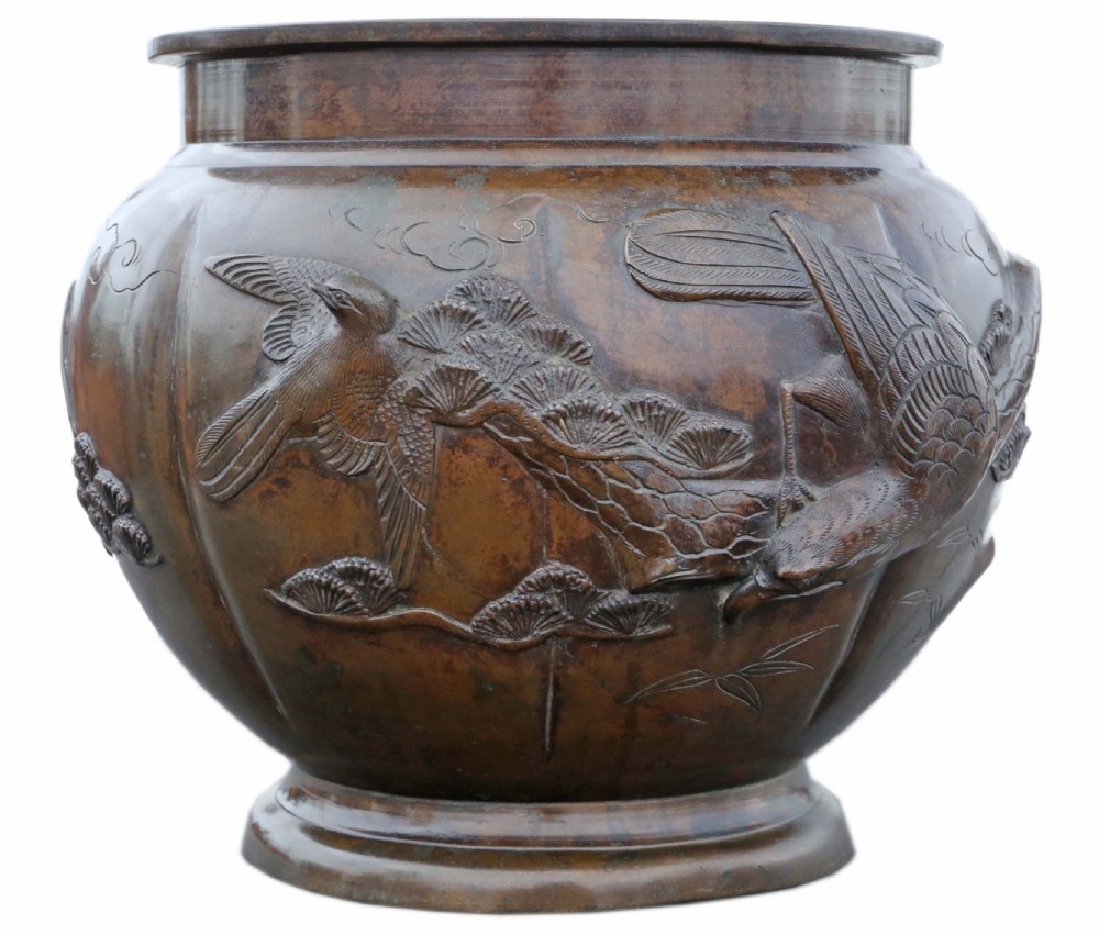 A Japanese Meiji period cast bronze jardiniere featuring a lobed body and high-relief carved decoration depicting birds amongst pine branches.