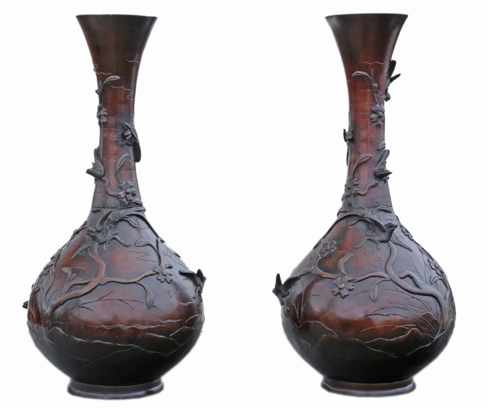 A pair of large Japanese bronze baluster vases featuring relief decoration of birds amidst flowering branches against a dark brown patinated finish.