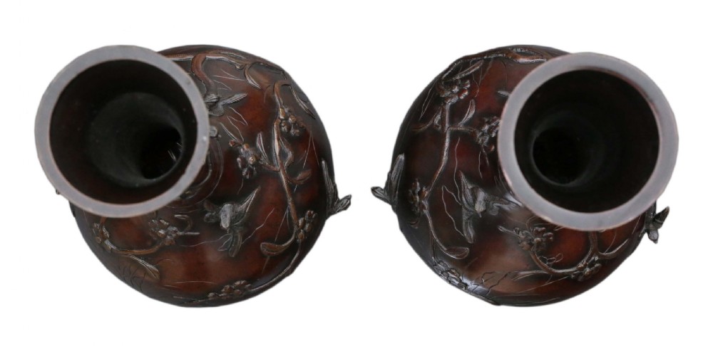 A pair of large Japanese bronze baluster vases featuring relief decoration of birds amidst flowering branches against a dark brown patinated finish. View III