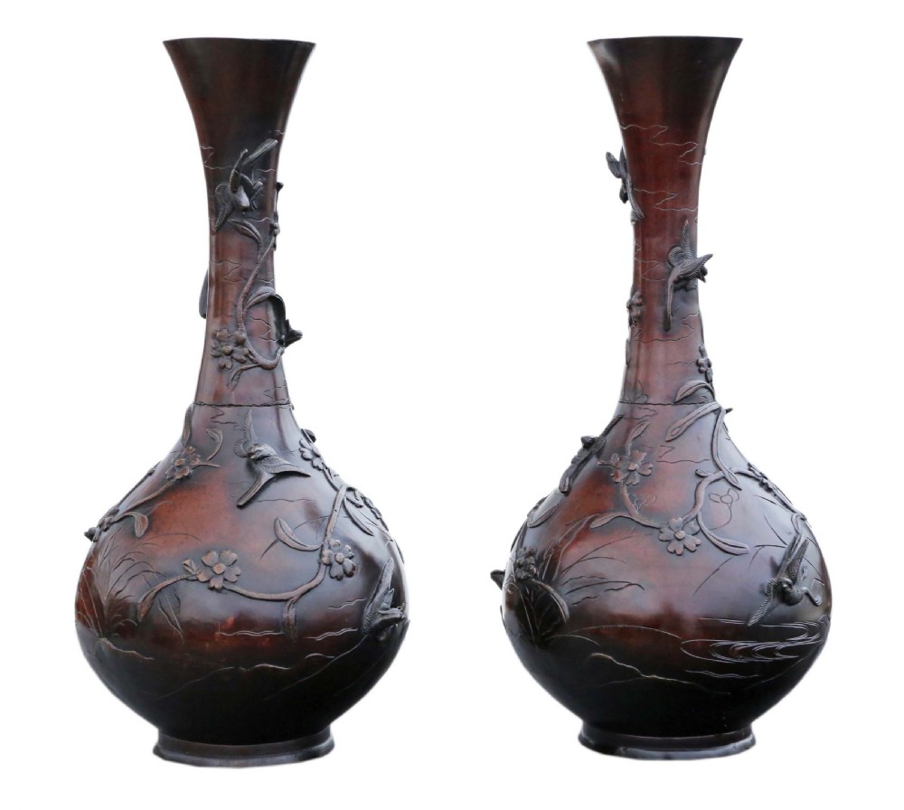 A pair of large Japanese bronze baluster vases featuring relief decoration of birds amidst flowering branches against a dark brown patinated finish. View V