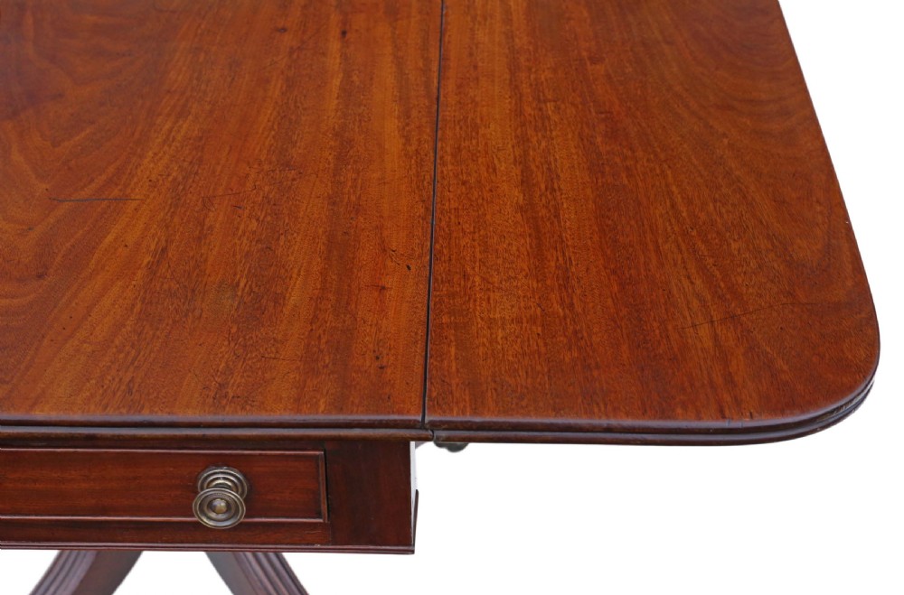 A Regency mahogany drop-leaf table featuring two hinged rectangular leaves, a single frieze drawer with brass handles, and a pedestal base with four reeded splayed legs fitted with brass castors. View III