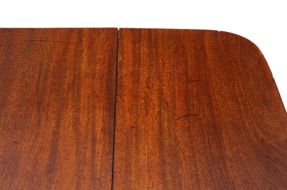 A Regency mahogany drop-leaf table featuring two hinged rectangular leaves, a single frieze drawer with brass handles, and a pedestal base with four reeded splayed legs fitted with brass castors. View IV