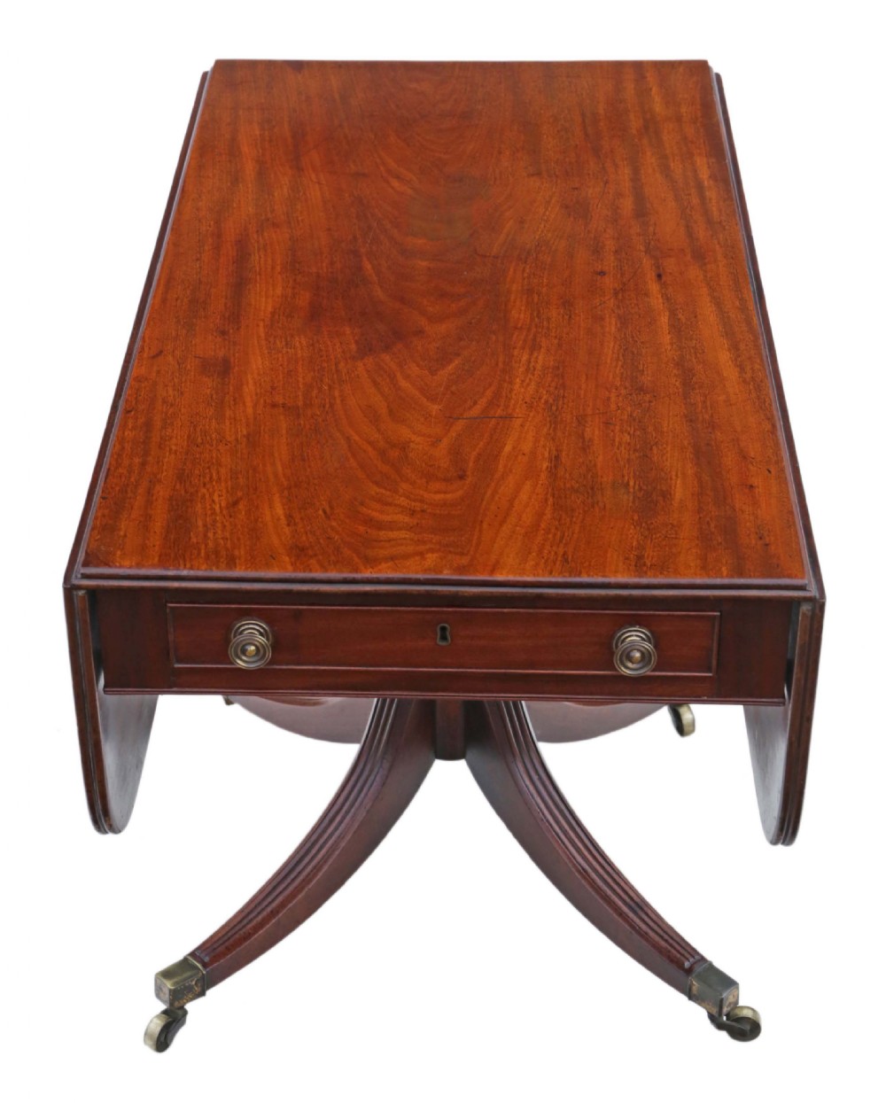 A Regency mahogany drop-leaf table featuring two hinged rectangular leaves, a single frieze drawer with brass handles, and a pedestal base with four reeded splayed legs fitted with brass castors. View VI