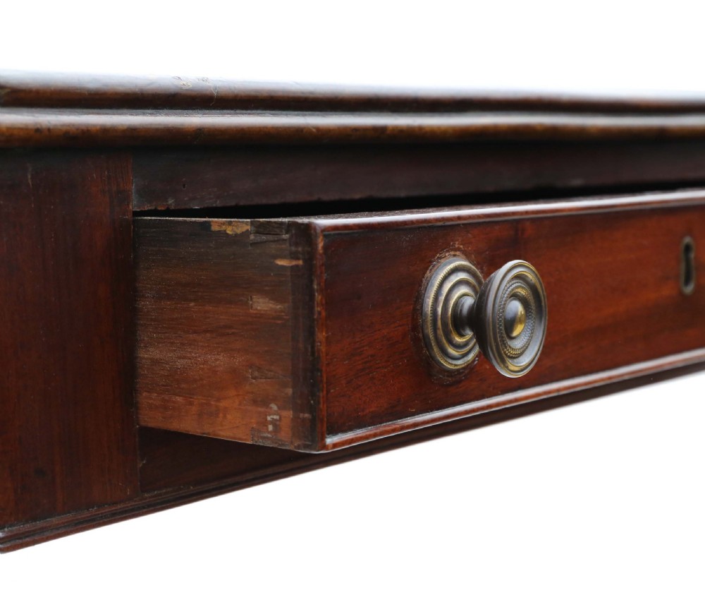 A Regency mahogany drop-leaf table featuring two hinged rectangular leaves, a single frieze drawer with brass handles, and a pedestal base with four reeded splayed legs fitted with brass castors. View VII
