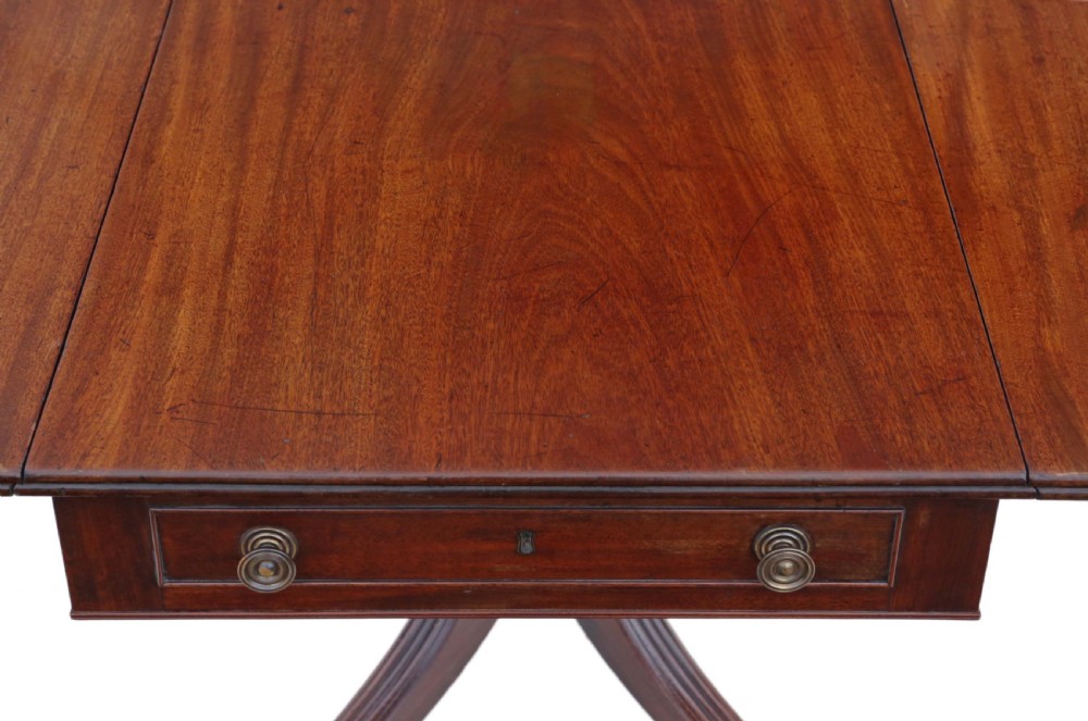 A Regency mahogany drop-leaf table featuring two hinged rectangular leaves, a single frieze drawer with brass handles, and a pedestal base with four reeded splayed legs fitted with brass castors. View X