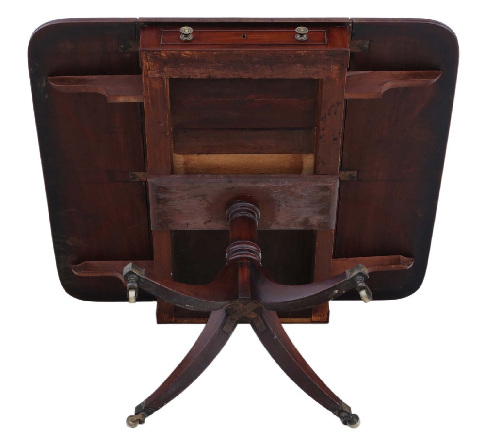 A Regency mahogany drop-leaf table featuring two hinged rectangular leaves, a single frieze drawer with brass handles, and a pedestal base with four reeded splayed legs fitted with brass castors. View XI